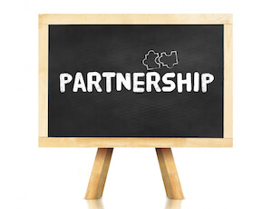 Image representing our diversity and inclusion consulting and advising approach.Partnership word and jigsaw icon on blackboard with easel and reflection on white background,Business concept